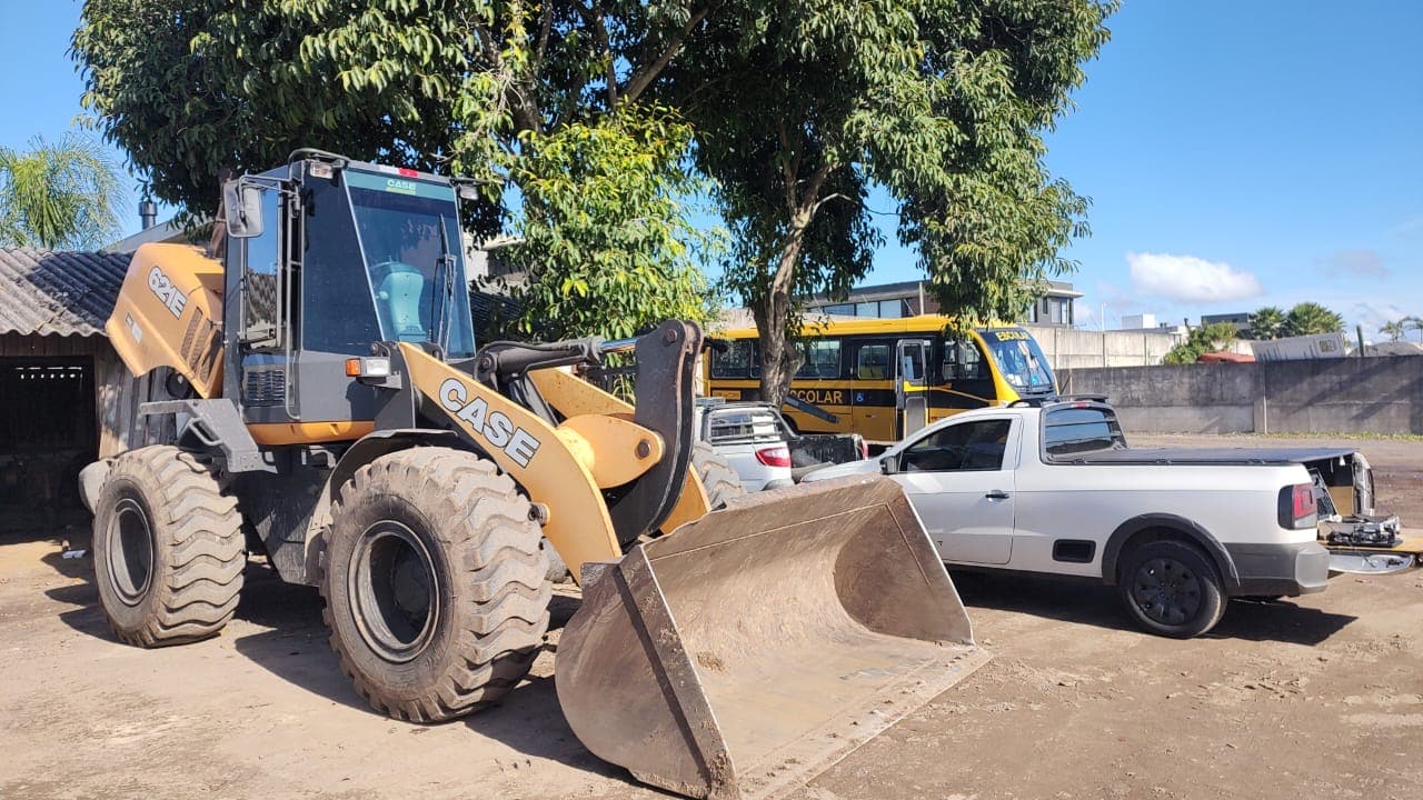 Pá-carregadeira no pátio, com a caminhonete de apoio ao lado
